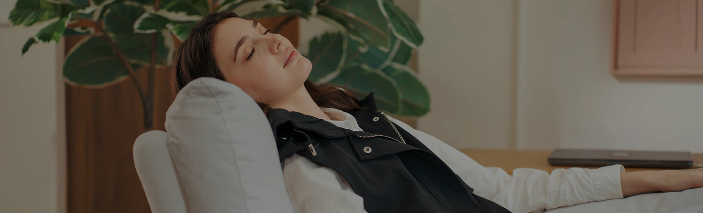 Woman relaxing on a white chair with a plant in the background