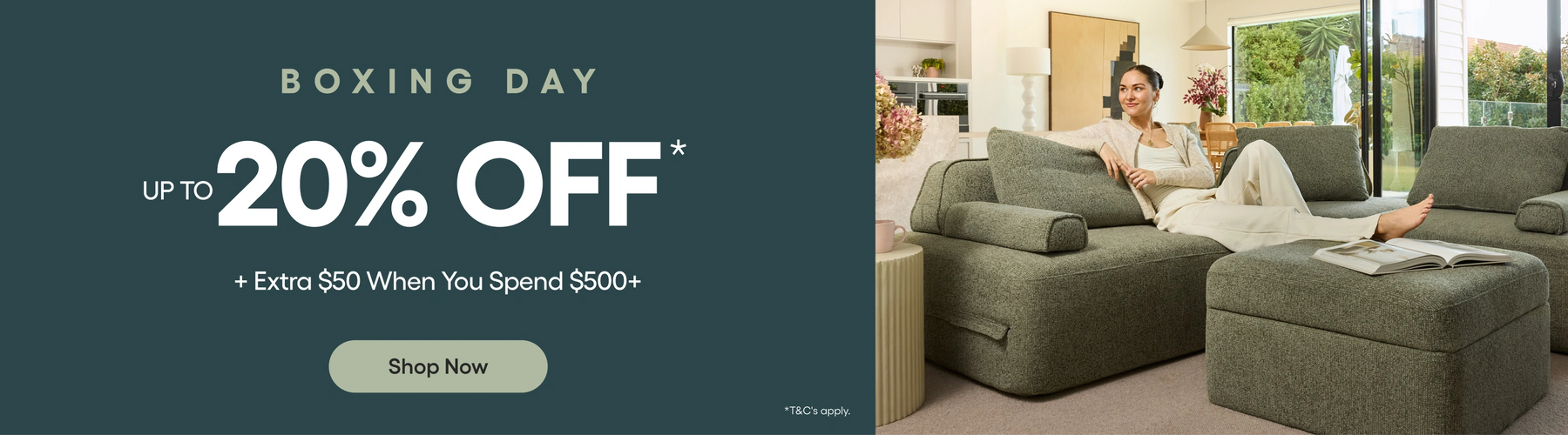 Promotional banner for Boxing Day sale with a woman sitting on a green sofa in a living room.